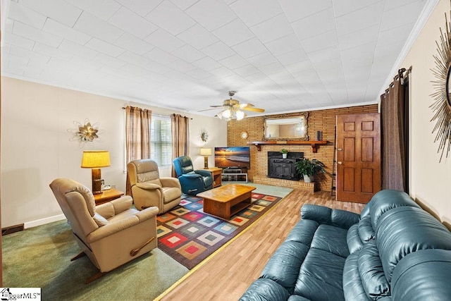 living room with wood finished floors, a ceiling fan, a fireplace, and crown molding