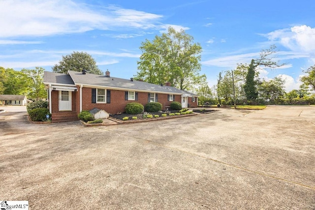 ranch-style home with a chimney and brick siding