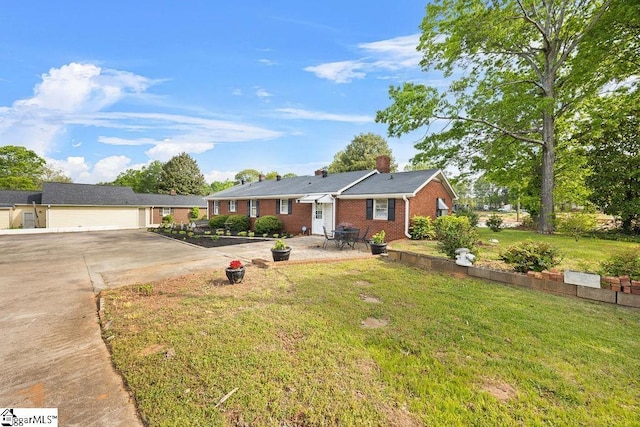 ranch-style home featuring a chimney, brick siding, a garage, a front yard, and concrete driveway
