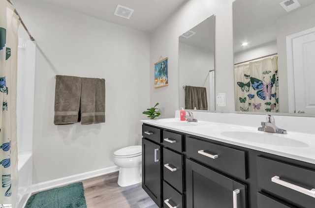 full bathroom with visible vents, wood finished floors, toilet, and double vanity