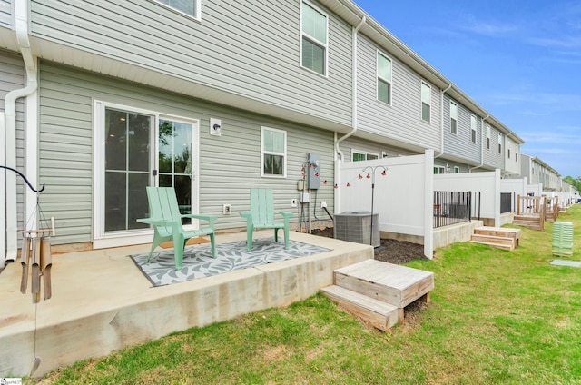 rear view of house with fence, cooling unit, and a yard