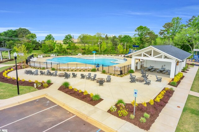 community pool featuring a patio, a fire pit, and fence