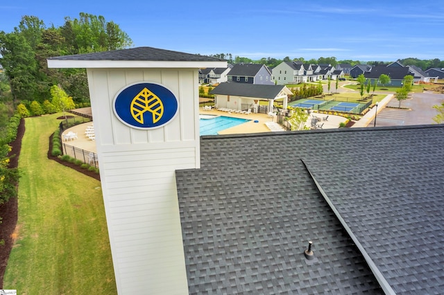 exterior details with a pool, a residential view, and roof with shingles