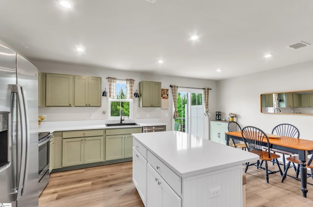 kitchen with green cabinetry, appliances with stainless steel finishes, light countertops, a sink, and visible vents