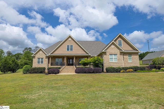craftsman house with covered porch, a front yard, and brick siding