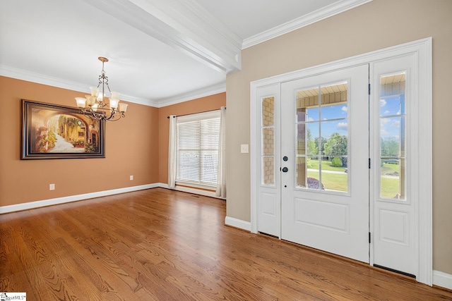 foyer featuring baseboards, wood finished floors, a notable chandelier, and crown molding
