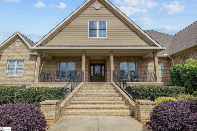 bungalow-style home featuring a porch, stairway, and brick siding