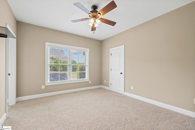 unfurnished room with light colored carpet, a ceiling fan, and baseboards