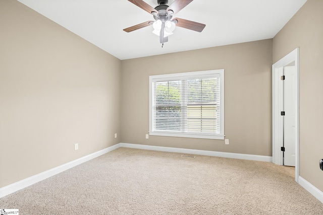 spare room featuring light colored carpet, a ceiling fan, and baseboards