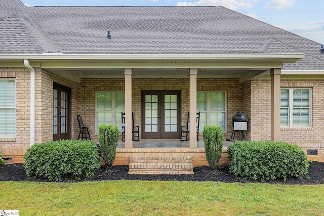 entrance to property featuring brick siding, french doors, and roof with shingles