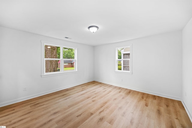 empty room with visible vents, light wood-style flooring, and plenty of natural light