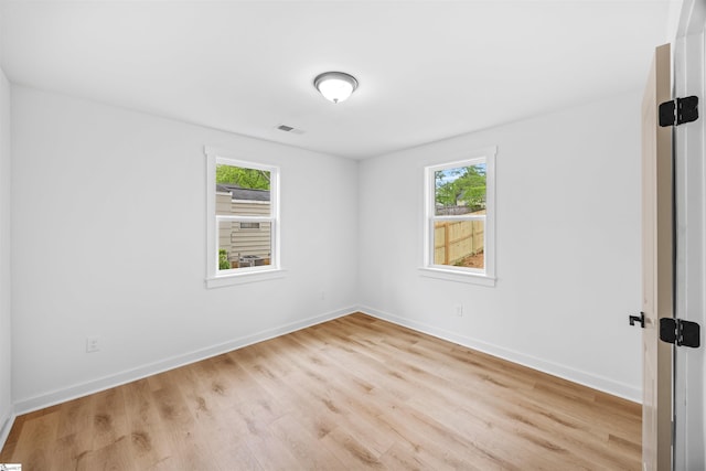 unfurnished room with wood finished floors, visible vents, and baseboards