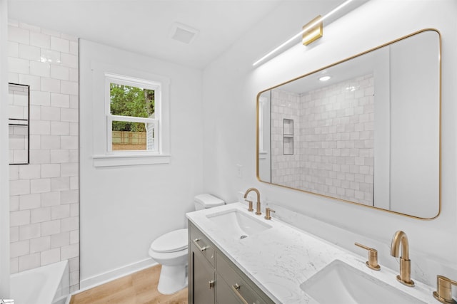 bathroom with toilet, double vanity, a sink, and wood finished floors