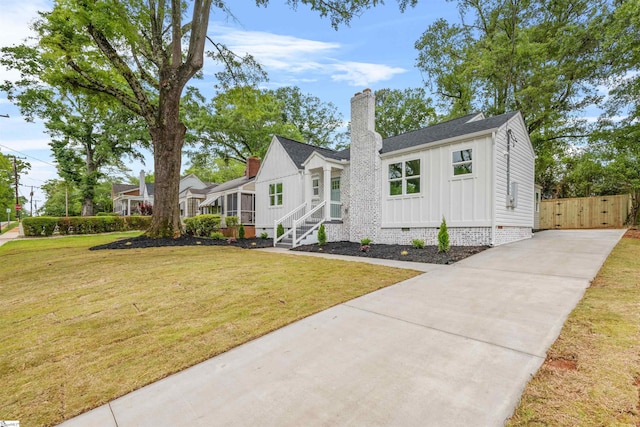 view of front of property with a chimney, board and batten siding, a front lawn, and driveway