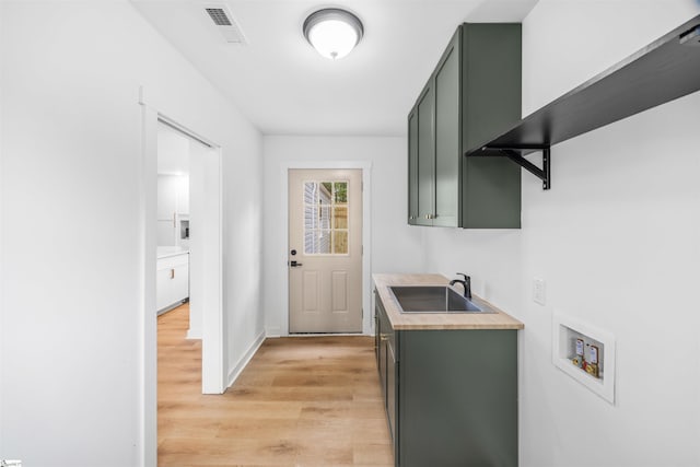 washroom featuring washer hookup, a sink, visible vents, light wood-type flooring, and cabinet space