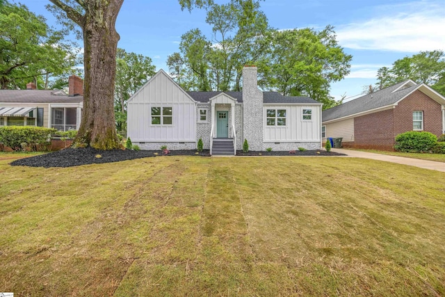 view of front of home featuring a chimney, board and batten siding, and a front yard