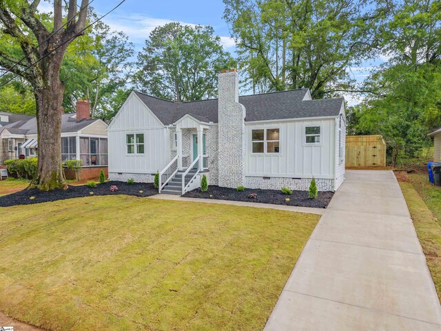 view of front of property featuring board and batten siding, crawl space, a front lawn, and a shingled roof