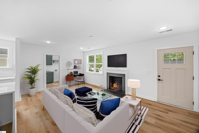 living room featuring visible vents, baseboards, light wood-type flooring, recessed lighting, and a fireplace