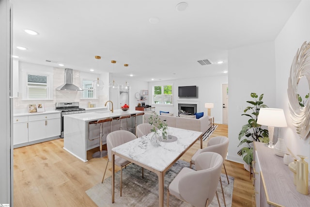 dining space featuring a fireplace, visible vents, recessed lighting, and light wood finished floors