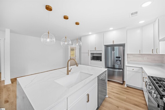 kitchen with light stone counters, a sink, white cabinets, and appliances with stainless steel finishes