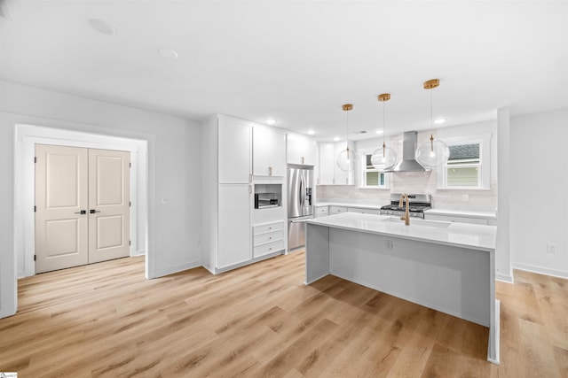 kitchen with tasteful backsplash, stainless steel appliances, light countertops, white cabinets, and wall chimney exhaust hood