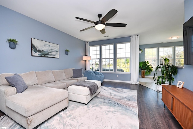 living area with dark wood-style floors, baseboards, and ceiling fan