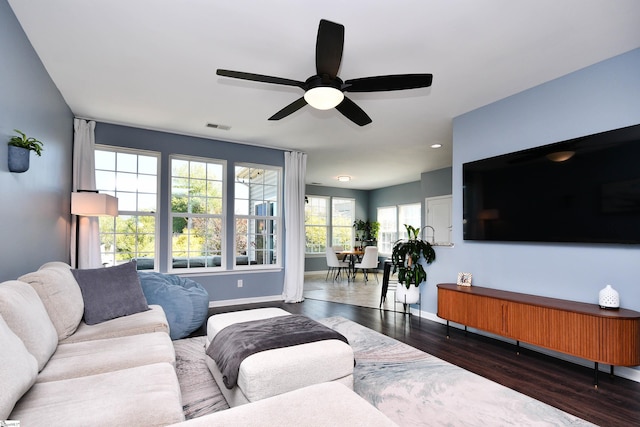 living room with wood finished floors, a ceiling fan, visible vents, and baseboards