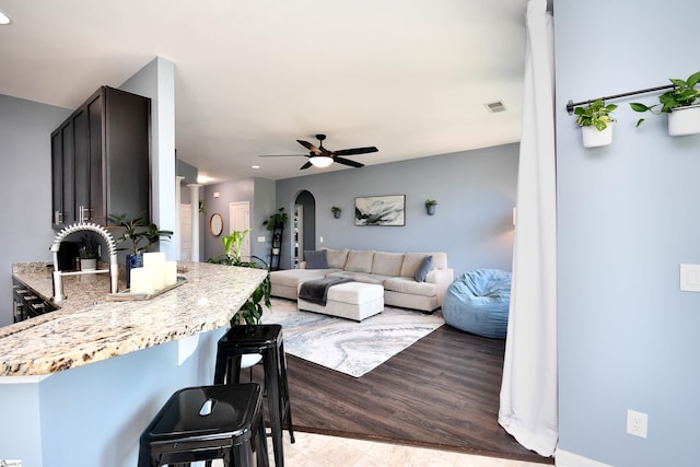 living room featuring arched walkways, ceiling fan, and visible vents