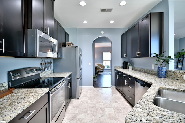 kitchen featuring recessed lighting, arched walkways, stainless steel appliances, a sink, and visible vents