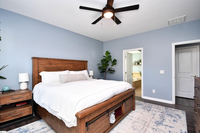 bedroom with baseboards, visible vents, wood finished floors, and connected bathroom