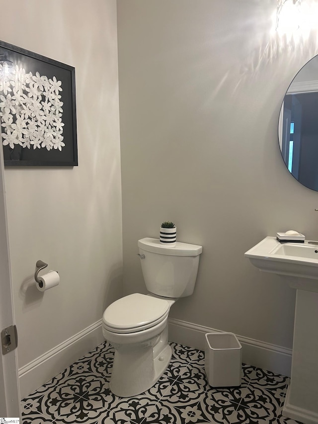 half bathroom featuring toilet, tile patterned flooring, and baseboards