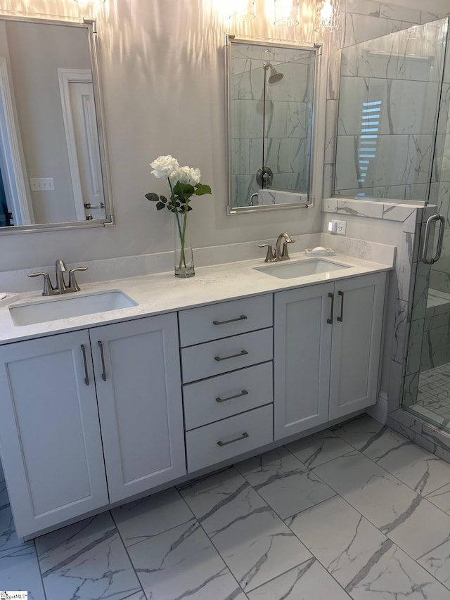 full bath with a stall shower, marble finish floor, double vanity, and a sink