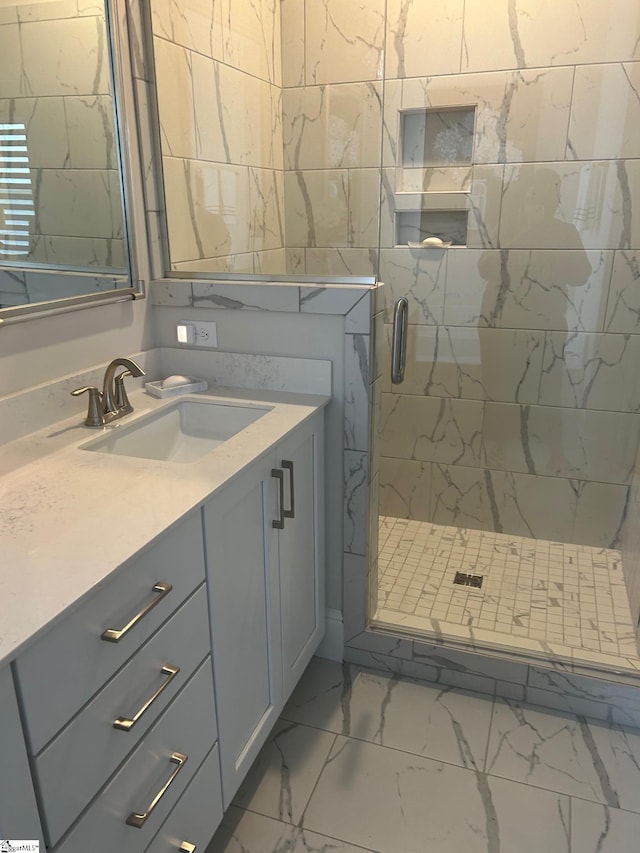 full bath featuring a stall shower, vanity, and marble finish floor