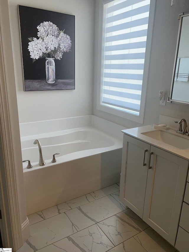 bathroom featuring a garden tub, marble finish floor, and vanity