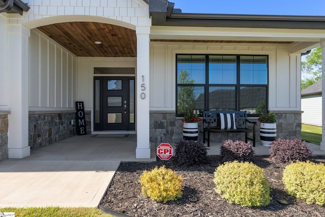 entrance to property with covered porch, board and batten siding, and stone siding