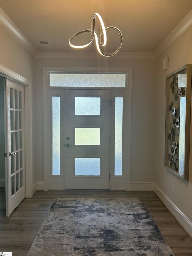 foyer with ornamental molding, wood finished floors, visible vents, and baseboards