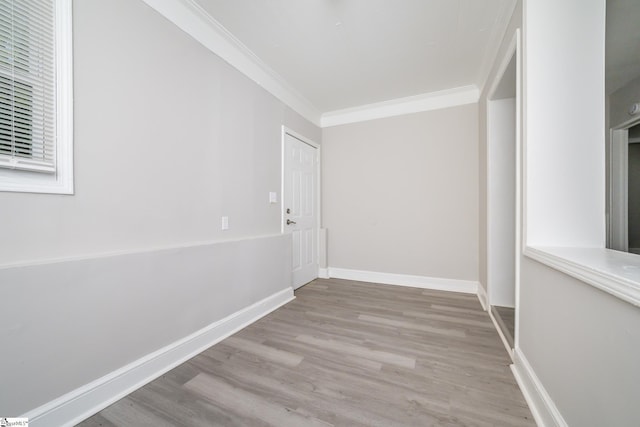 empty room featuring baseboards, wood finished floors, and ornamental molding