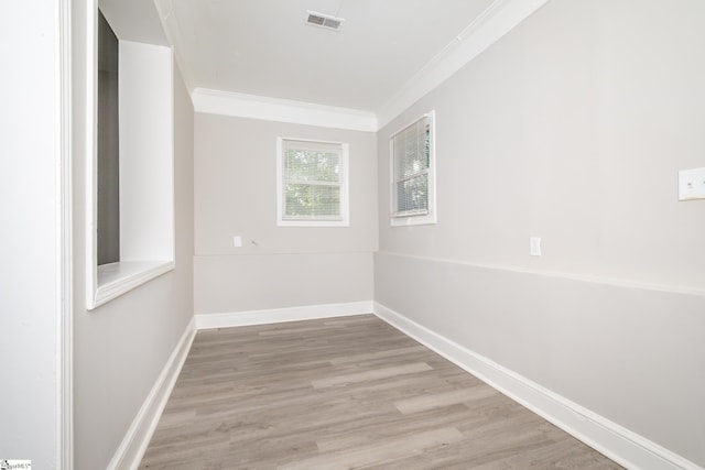 spare room featuring crown molding, visible vents, wood finished floors, and baseboards