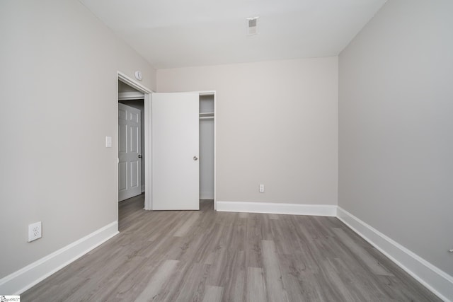 unfurnished bedroom with visible vents, wood finished floors, and baseboards