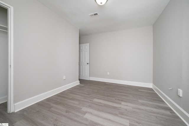 unfurnished bedroom featuring baseboards, visible vents, wood finished floors, and a closet