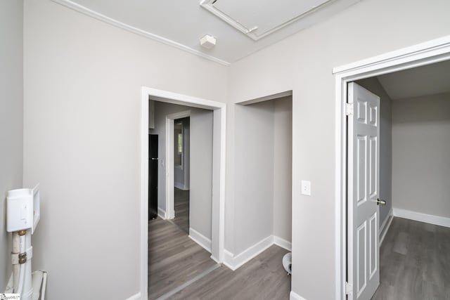 hallway featuring attic access, wood finished floors, and baseboards