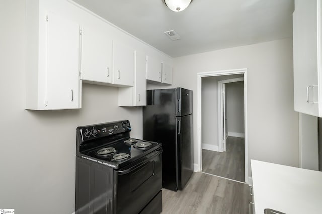 kitchen with light wood-style floors, white cabinets, black appliances, baseboards, and visible vents