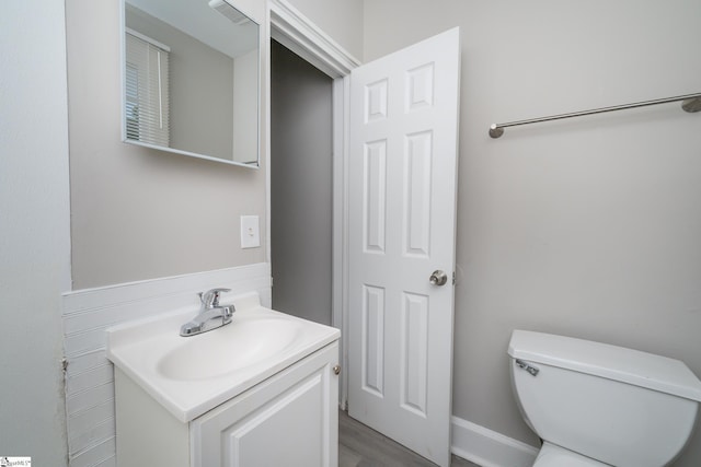 bathroom featuring toilet, visible vents, wood finished floors, and vanity