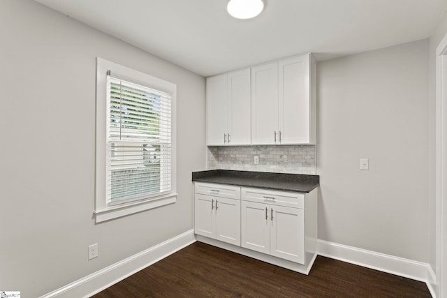 kitchen featuring baseboards, white cabinets, dark countertops, and decorative backsplash