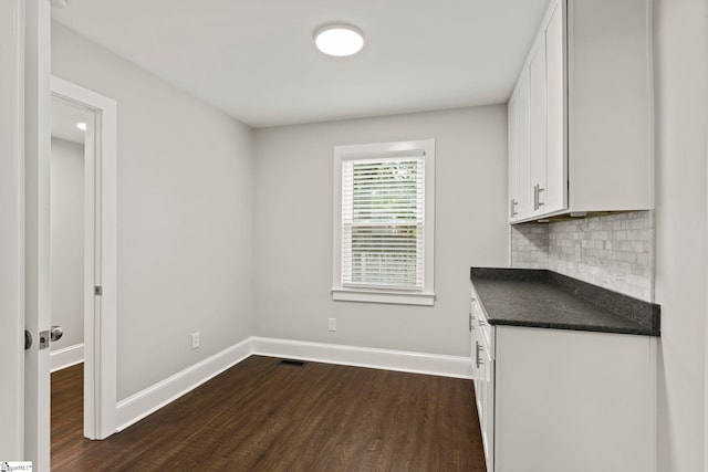 interior space with dark wood-style floors, visible vents, and baseboards
