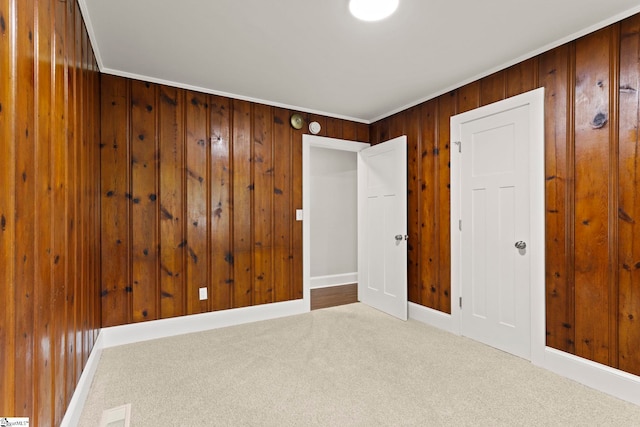 spare room featuring baseboards, wood walls, and carpet flooring