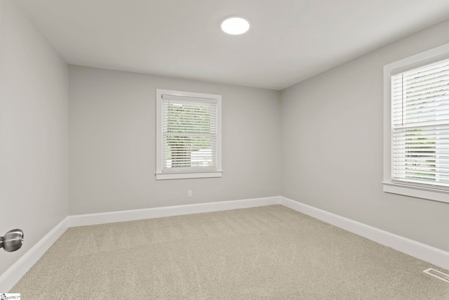 unfurnished room featuring baseboards, visible vents, and light colored carpet