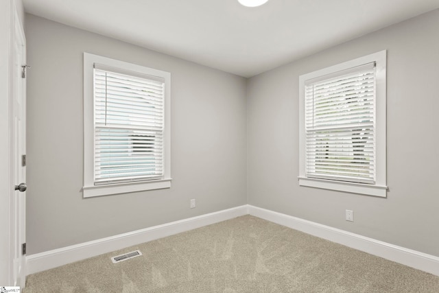 empty room featuring visible vents, carpet floors, and baseboards