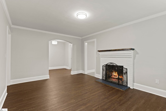 unfurnished living room with a brick fireplace, crown molding, dark wood finished floors, and arched walkways