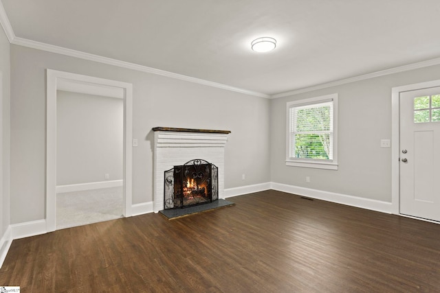 unfurnished living room with dark wood-type flooring, crown molding, baseboards, and a brick fireplace